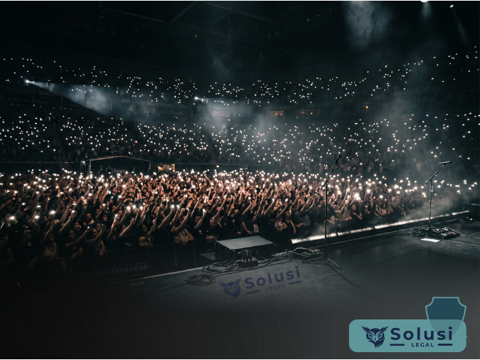 Penonton konser mengangkat ponsel dengan lampu layar menyala, ilustrasi aturan hukum larangan merekam di konser